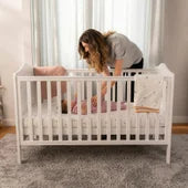 Photo of mother tending to baby in cot
